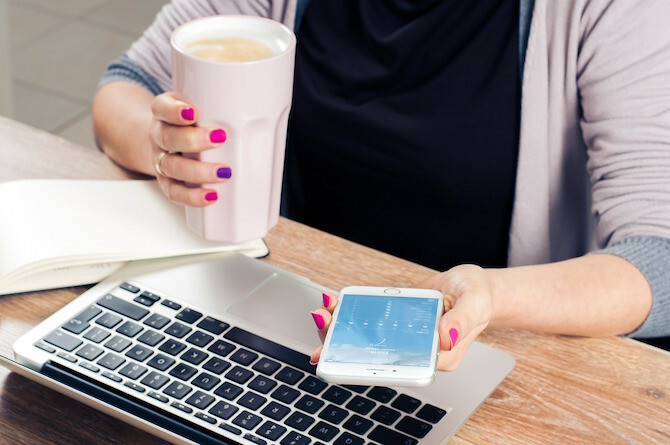 Femeie care bea cafea la telefon și Mac