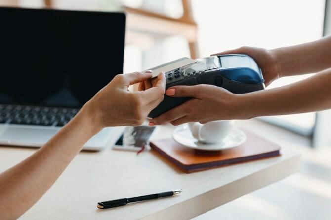 Cineva care plătește mărfurile care folosesc NFC pe un card de credit.