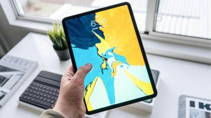 Țineți în mână un iPad Pro cu tapet strălucitor