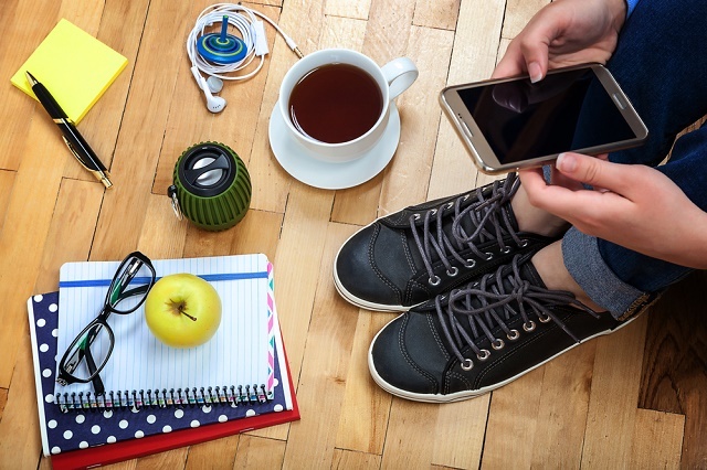 Persoană cu smartphone, ceașcă de cafea, notebook etc.